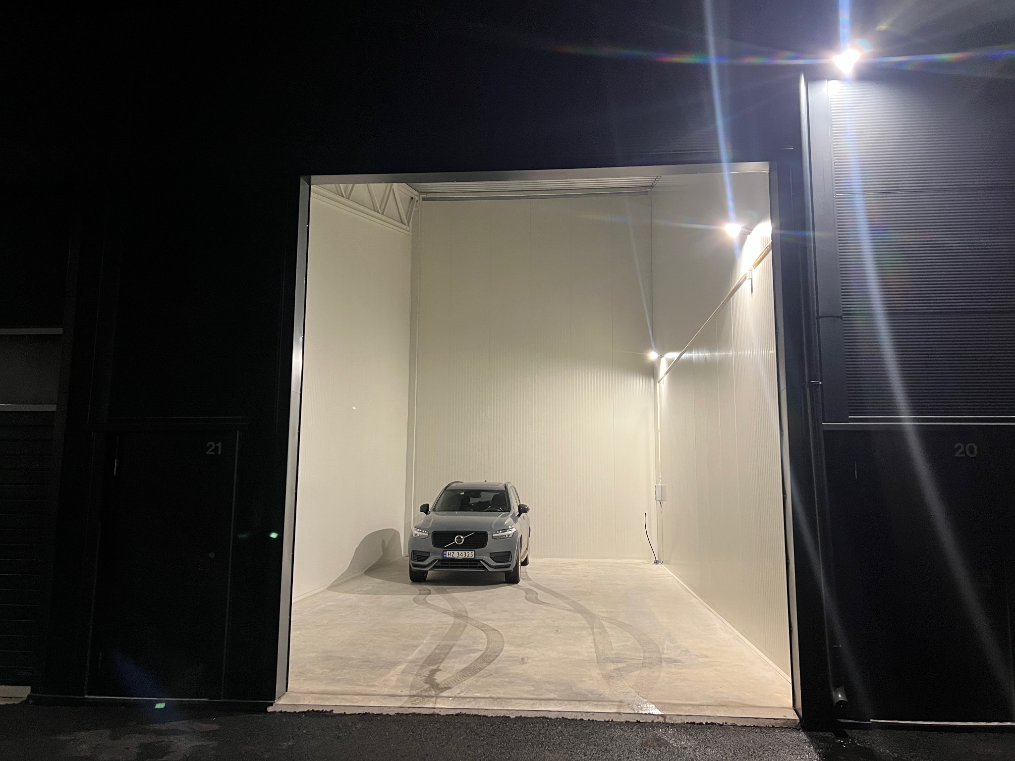 Lagerseksjon med bil parkert inni, port åpen om kvelden